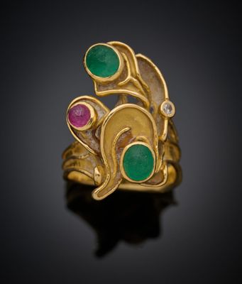 un gros plan d'une bague en or sertie de pierres vertes et roses