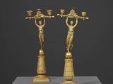 une paire de figurines en bronze représentant des femmes tenant des paniers, posées sur un socle