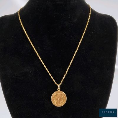 un collier en or avec une pièce de monnaie sur le cou d'un mannequin