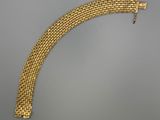 gros plan d'un bracelet en or sur une surface grise