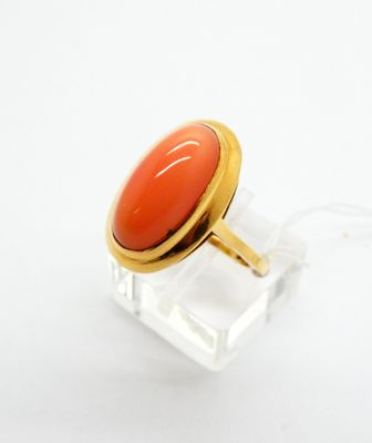 une image représentant une bague ornée d'une pierre rouge posée sur une surface transparente