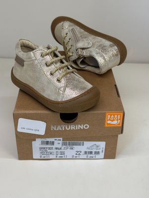 une paire de chaussures pour bébé dans une boîte posée sur une surface blanche