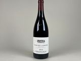 une bouteille de vin rouge posée sur une table blanche