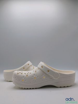 the white crocs are lined up with holes and holes on them