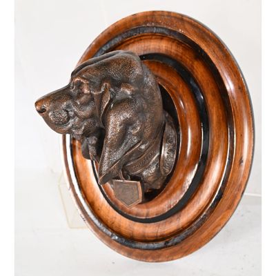 an image of a bronze dog head mounted on a wooden plaque
