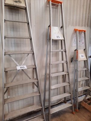 several ladders are lined up against a wall in a warehouse