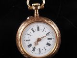 a gold pocket watch with roman numerals on the face