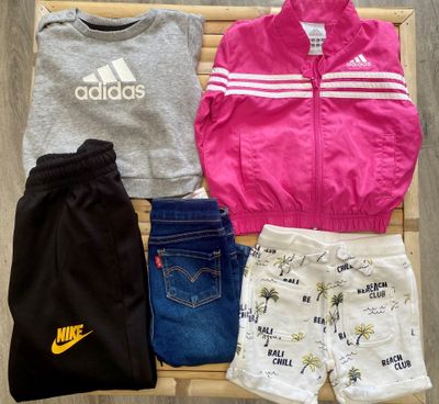 a pile of clothing that includes a jacket, shorts, and shoes