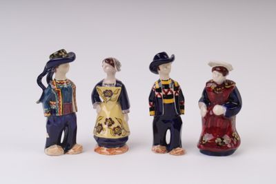 three figurines of people dressed in traditional clothing standing next to each other