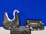 three pieces of black purses on a white table against a blue wall