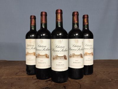 four bottles of red wine are lined up on a wooden table