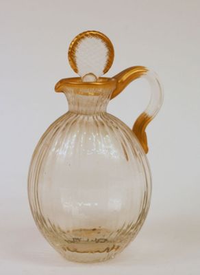 un pichet en verre transparent avec une anse dorée sur fond blanc