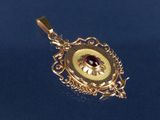 un pendentif en or orné d'une pierre rouge au centre