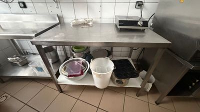 a kitchen with a stainless steel table and buckets on the floor