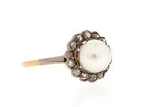 a close up of a pearl and diamond ring on a white background