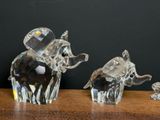 three crystal figurines of elephants on a table with a black background