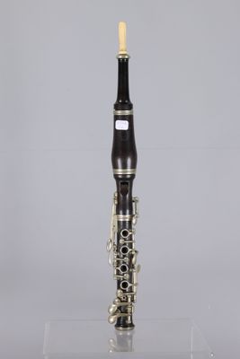a close up of a clarinet on a clear surface with a gray background