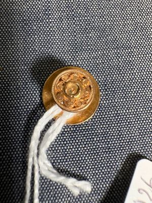 un bouton doré auquel est attaché un cordon blanc