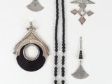 an assortment of silver and black jewelry on a white surface