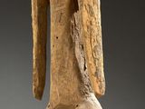a wooden statue of a man standing on a black base