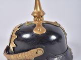 an old helmet with a gold spike on top on a white surface