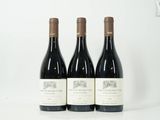 trois bouteilles de vin rouge sont alignées sur une surface blanche