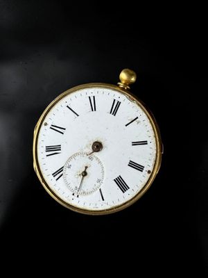 a gold pocket watch with roman numerals on the face