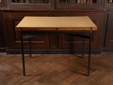 une petite table avec un plateau en bois, placée devant une bibliothèque