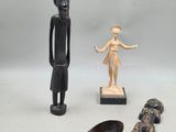 trois figurines en bois et une cuillère en bois posées sur une surface blanche