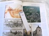 an open book with pictures of a city and a bookmark on it