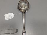 a silver spoon with a tag on it next to a pair of scissors