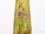 a yellow vase with flowers on it sitting on a stand
