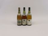 trois bouteilles de vin posées les unes à côté des autres sur une surface blanche