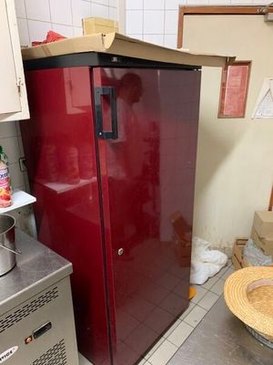 un réfrigérateur rouge dans une cuisine, à côté d'une cuisinière