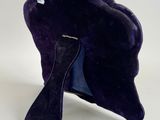 a purple hat on a stand on a white surface