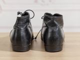 pair of black leather ankle boots with laces on a wooden surface