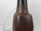 a brown vase with a black lid on a white table