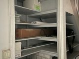 a closet with shelves and a chair in it