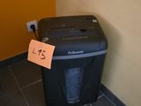 une déchiqueteuse à papier posée par terre près d'un mur