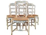 four wooden chairs with blue and white designs on them sitting next to each other