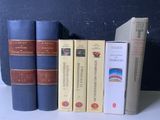 Plusieurs livres sont alignés sur une étagère devant un mur noir