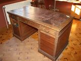 a wooden desk with a marble top in the middle of a room