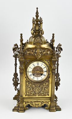 a gold clock that is sitting on a white surface