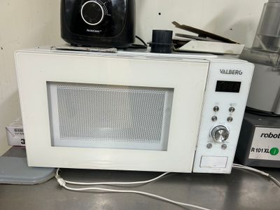 un micro-ondes posé sur un plan de travail, à côté d'un mixeur et d'un mixeur