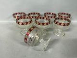 six verres à vin ornés de motifs rouges et dorés, posés sur une surface blanche