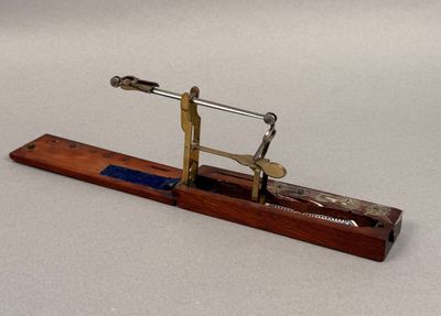 a small metal object on a wooden stand on a white surface