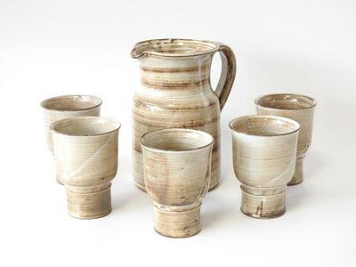 quatre tasses et un pichet posés les uns à côté des autres sur une table