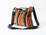 un sac à main rayé orange, noir et blanc, muni d'une bandoulière noire