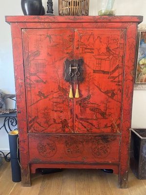 un meuble rouge surmonté d'une horloge, dans un salon