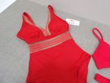 red swimsuit and panties on a bed with a tag on it
